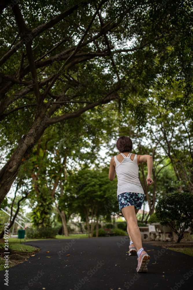 Asian woman running in the park, with greenery environment Asian woman running in the park, with greenery environment
