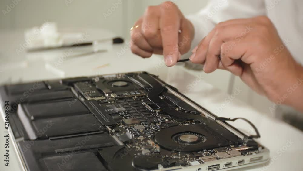 A man is repairing a laptop. The concept of computer repair. Close up of man repair laptop motherboard with a screwdriver. Maintenance of the hardware of the motherboard. Disc holder, computer repair