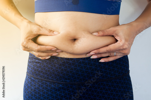 Woman measuring her belly fat with her hands close up