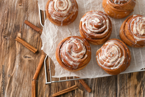 Cooling rack with tasty cinnamon buns on wooden table