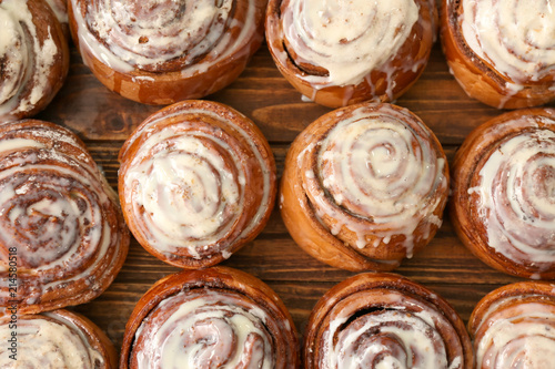 Tasty homemade cinnamon buns with glaze on wooden table, top view