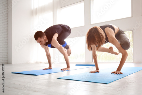 Fototapeta Naklejka Na Ścianę i Meble -  Sporty man and woman practicing yoga indoors