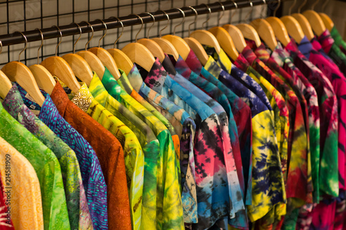 Fashion clothes on clothing rack - bright colorful closet. Closeup of rainbow color choice of trendy wear on hangers in store closet.