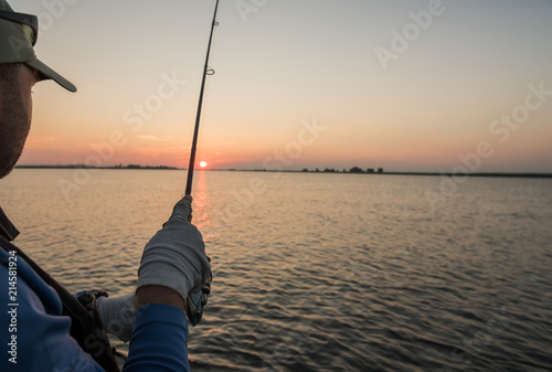 A fisherman fishing at dawn on a river. Close-up. 