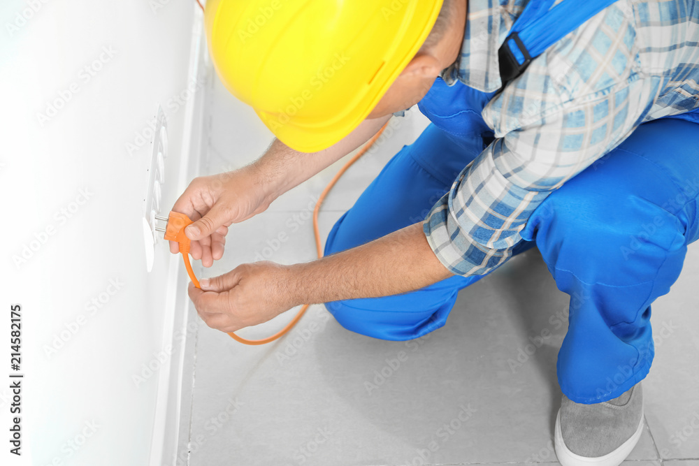 Male electrician inserting plug into socket in order to check its serviceability