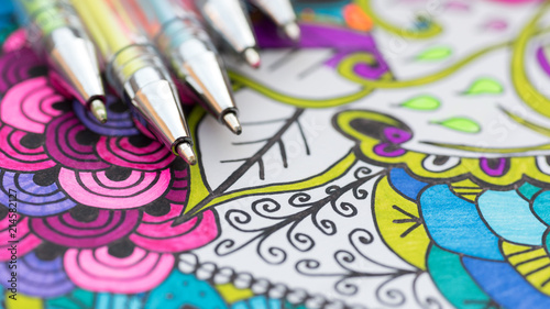 Adult coloring book, new stress relieving trend. Art therapy, mental health, creativity and mindfulness concept. Adult coloring page with pastel colored gel pen close up. photo