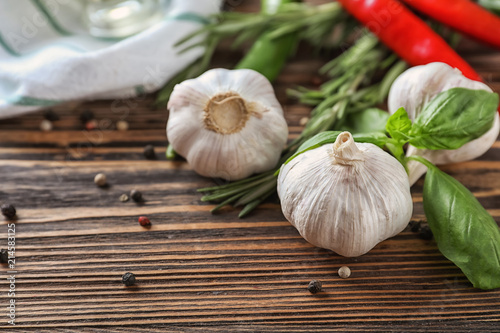 Fresh garlic with spices and herbs on wooden background