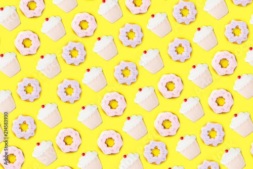 Sweets and desserts concept, donuts and cupcake cookies creative layout, simple pattern on trendy bright yellow background, above