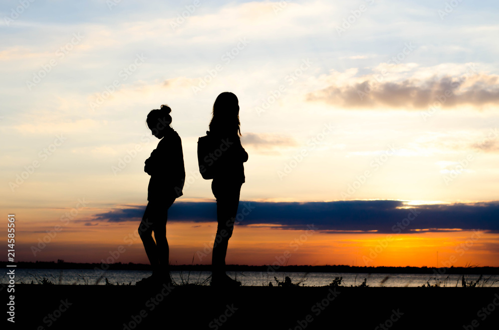 Couple woman silhouette standing sad  during sunset and beautiful sky.