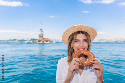Photography Beautiful woman traveler eats traditional Turkish street food simit(bagel)in fro