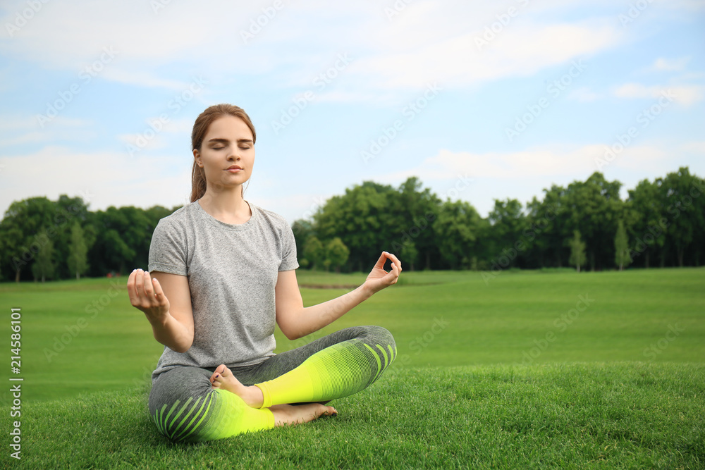 Fototapeta premium Young woman practicing yoga in park