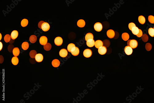 Christmas glowing lights on dark background, blurred view
