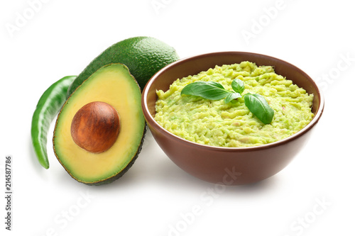 Bowl with tasty guacamole, chili pepper and ripe avocados on white background