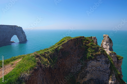 Picturesque landscape on the cliff of Etretat. la Manneporte natural rock arch wonder, cliff and beach. Coast of the Pays de Caux area in sunny spring day. Etretat, Normandy, France