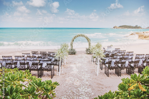 Beautiful beach wedding venue setting with flowers, floral decoration on arch, panoramic ocean view