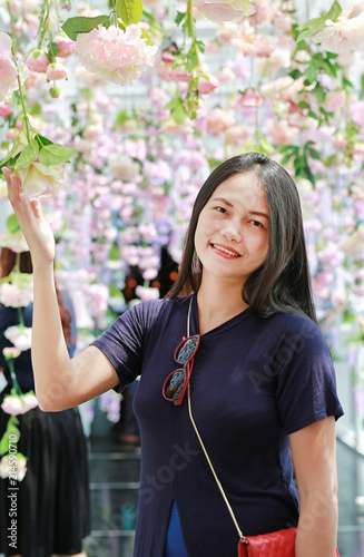 Portrait of asian woman with garden flowers on a sunny day. Surrounds the flowering.