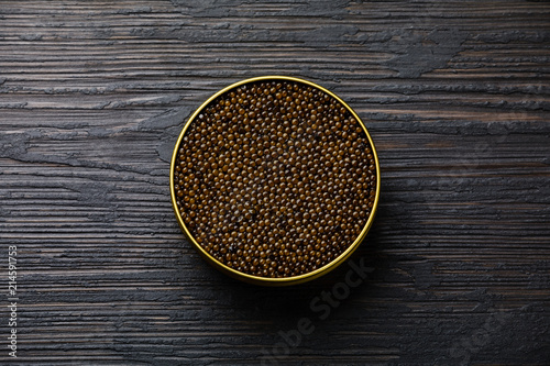 Black caviar in can on black wooden background