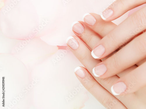Manicure  Hands spa Beautiful woman hands  soft skin  beautiful nails with pink rose flowers petals. Healthy Woman hands. Beauty salon. Beauty treatment. Female nails with beautiful french manicure