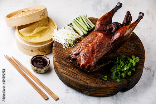 Peking Duck set with fresh cucumber, onion, cilantro, Hoysin sauce and pancakes on wooden cutting board on dark background