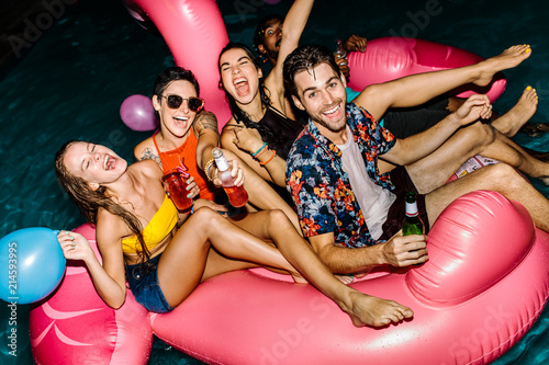 Group of men and women enjoying at pool party photo