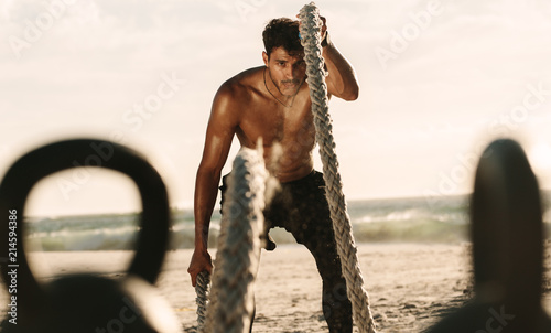 Obraz na plátně Man doing workout with battle ropes and kettlebells