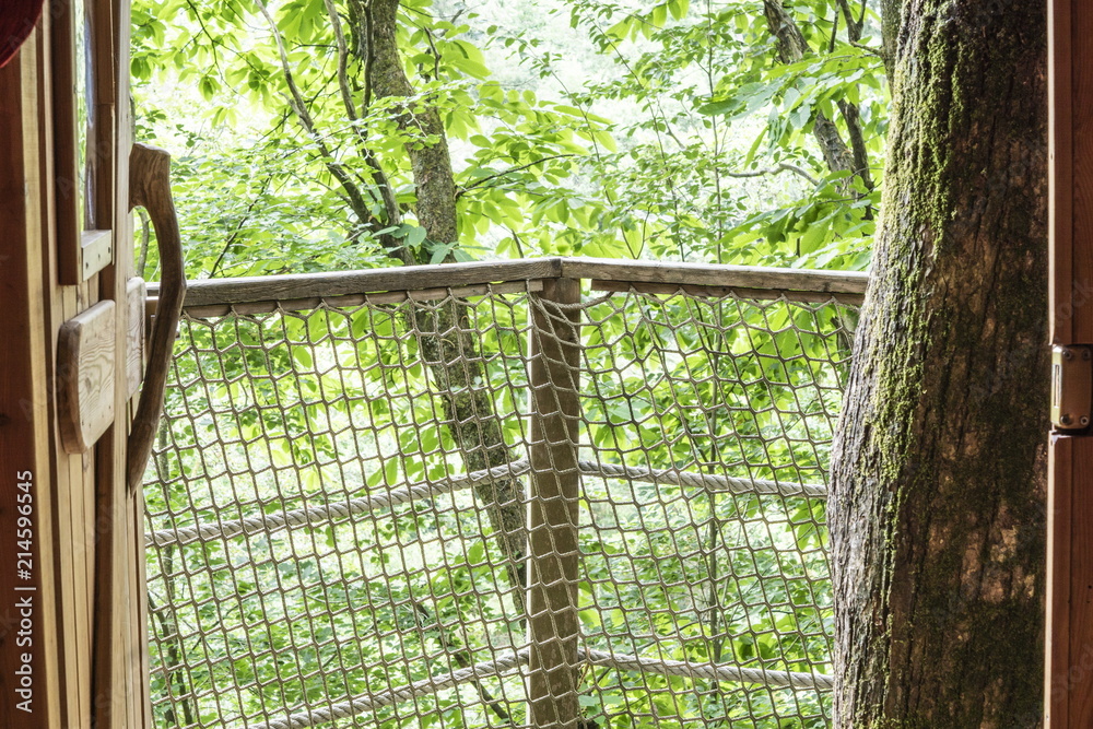 Cabane dans les arbres. La porte en bois ouverte, balcon avec Filet de garde -corps Photos | Adobe Stock