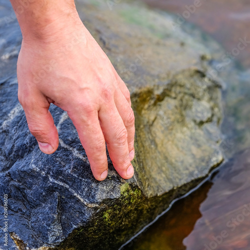 Hand putting stone on stacking stones on the riverside. The stones are stacked on the river side. photo