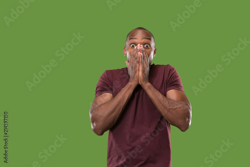 The young attractive man looking suprised isolated on green