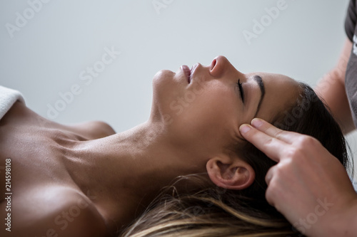 Anonymous masseur massaging face skin of woman