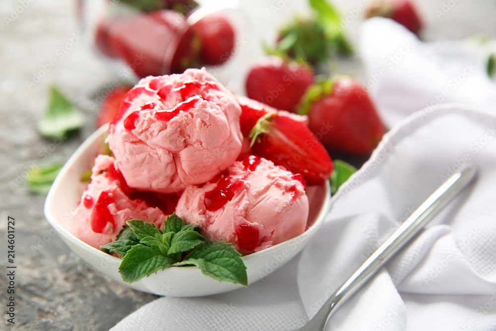 Bowl with delicious strawberry ice-cream on grey table