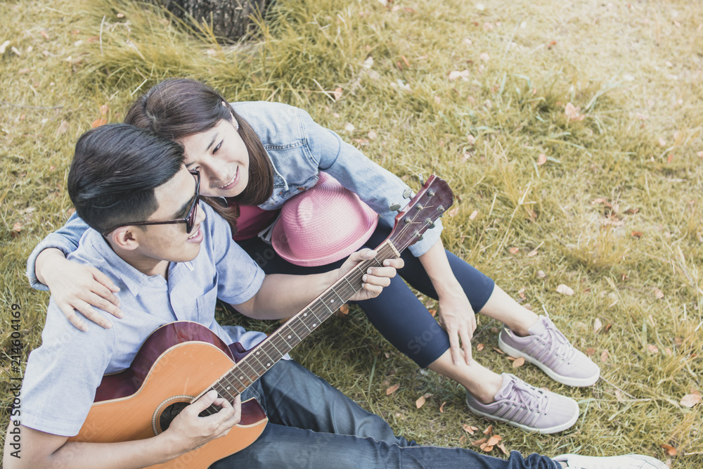 Asian lover couple play guitar in park, romantic and valentine day concept