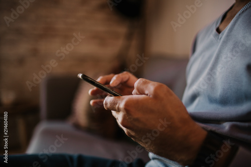 Close-up view of male hand holding smartphone. Blurred background.Blogger using mobile gadget. Horizontal.Colors profile