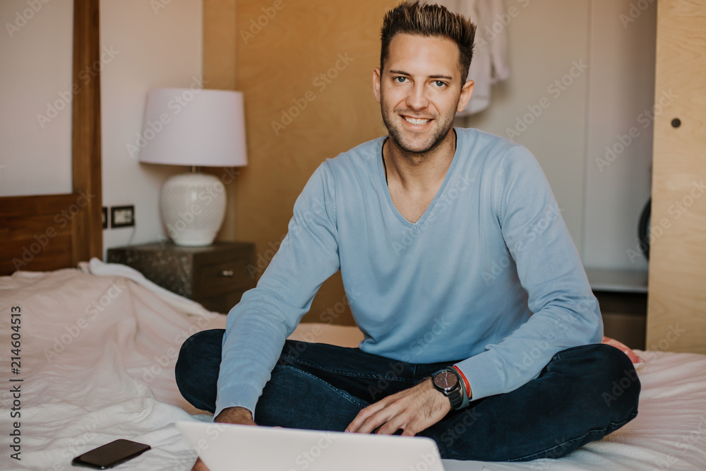 Working moments at home.Happy caucasian coworker man in casual clothes working on laptop at modern apartment. Blurred background