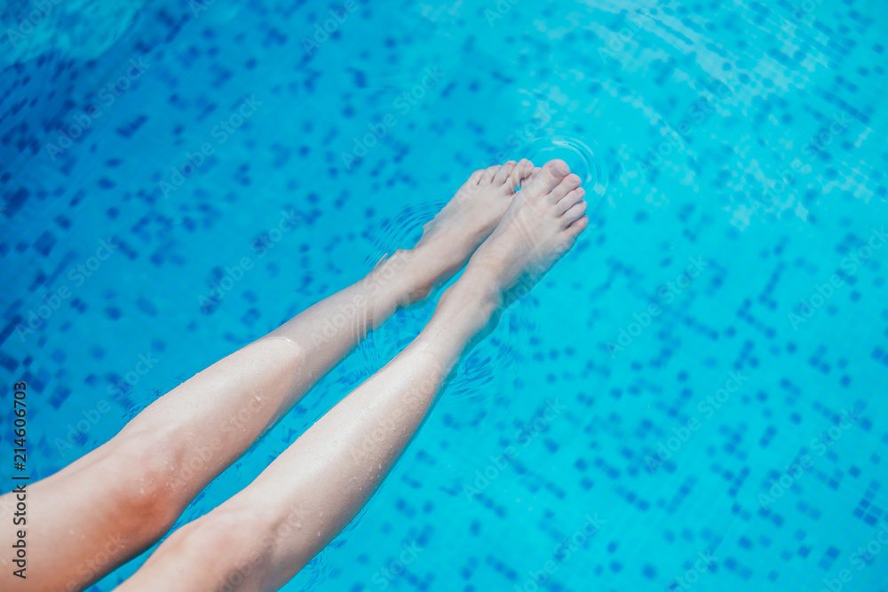 Beautiful female legs in the blue swimming pool water.