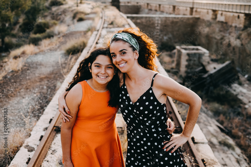 .Two young sisters enjoying a fun summer afternoon on abandoned train tracks dancing and laughing. Family vacation. Lifestyle.