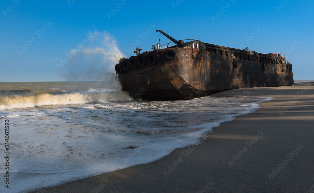 old rusty iron boat strand in the beach, Waves breaking over the ship