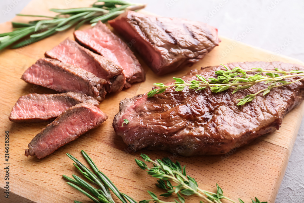 Tasty grilled meat with herbs on wooden board Tasty grilled meat with herbs on wooden board