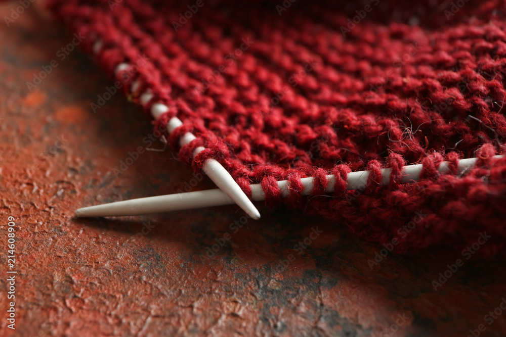 Knitting needles with unfinished clothes on table, closeup Knitting needles with unfinished clothes on table, closeup