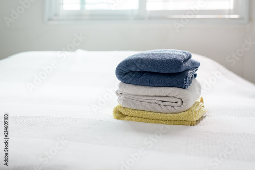 Stack of plush hotel clean soft,Blue,Yellow towel on bed decoration in bedroom interior © gballgiggs