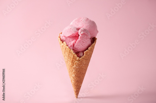 Fototapeta Waffle cone with delicious strawberry ice-cream on color background
