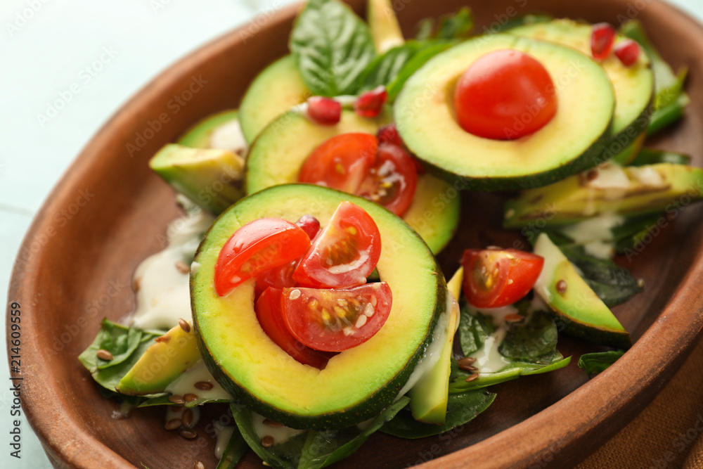 Plate with tasty avocado salad on table, closeup