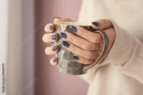 Young woman with beautiful manicure holding cup of beverage, closeup