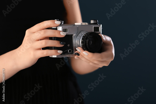 Young woman with beautiful manicure and retro photo camera on dark background, closeup