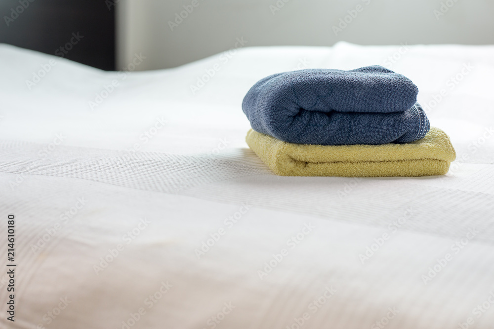 Stack of plush hotel clean soft towels White,Blue,Yellow towel on bed Stack of plush hotel clean soft towels White,Blue,Yellow towel on bed