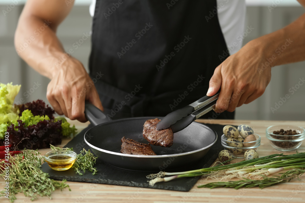 Man preparing delicious meat with fresh spices in kitchen