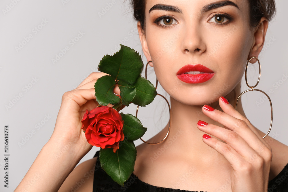 Young woman with beautiful manicure and flower on grey background