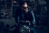 Young Biker in Sunglasses on Motorcycle in Garage.