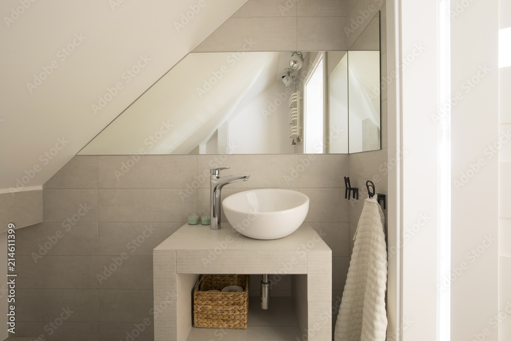 Mirror above washbasin in beige bathroom interior on attic with towel. Real photo - obrazy, fototapety, plakaty 
