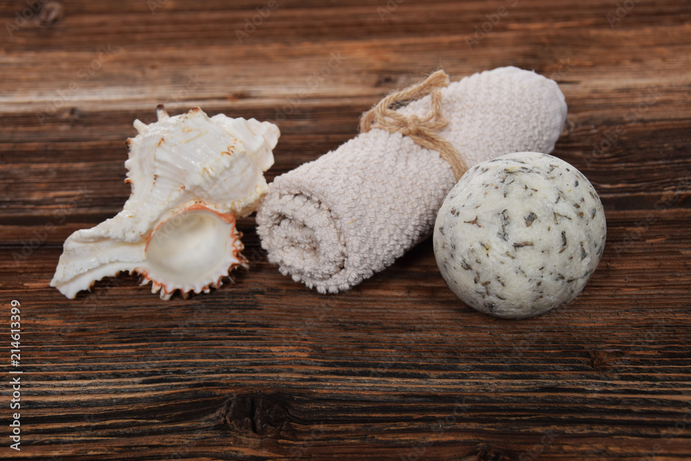 herbal white bath ball white towel and sea shell in a bathtub on a brown background