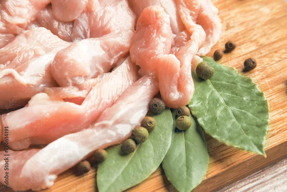 Pieces of fresh chicken fillet, bay leaf and pepper on a wooden background Pieces of fresh chicken fillet, bay leaf and pepper on a wooden background